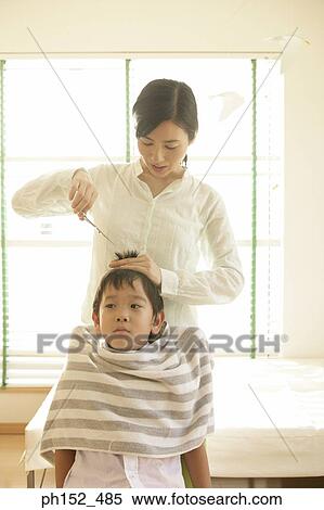 Stock Photography - Mid adult woman cutting her son's hair. Fotosearch
