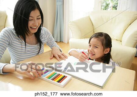 Stock Photo - Mid adult woman drawing with her daughter. Fotosearch