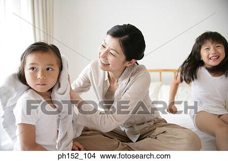 Mid adult woman drying her daughter's hair on the bed View Large Photo Image Picture - Mid adult woman drying her daughter's hair on the bed. Fotosearch