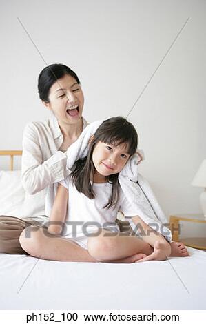Mid adult woman drying her daughter's hair on the bed View Large Photo Image Stock Image - Mid adult woman drying her daughter's hair on the bed. Fotosearch