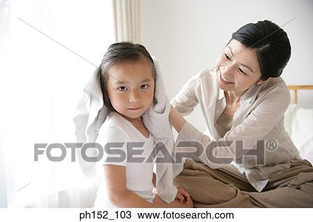 Mid adult woman drying her daughter's hair on the bed View Large Photo Image Stock Image - Mid adult woman drying her daughter's hair on the bed. Fotosearch