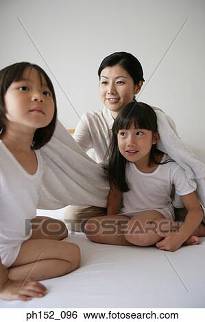 Mid adult woman drying her daughter's hair on the bed and smiling View Large Photo Image Stock Photograph - Mid adult woman drying her daughter's hair on the bed and smiling. Fotosearch
