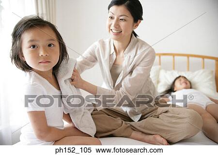 Mid adult woman drying her daughter's hair on the bed View Large Photo Image Stock Photography - Mid adult woman drying her daughter's hair on the bed. Fotosearch