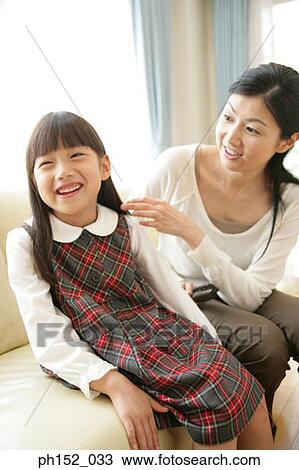 Mid adult woman holding a hairbrush and looking at her daughter View Large Photo Image Stock Image - Mid adult woman holding a hairbrush and looking at her daughter. Fotosearch