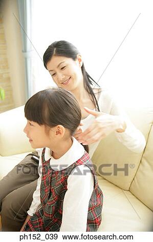 Mid adult woman holding her daughter's hair View Large Photo Image Stock Photo - Mid adult woman holding her daughter's hair. Fotosearch