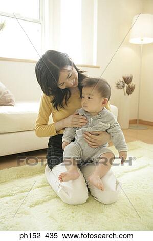 Stock Photography - Mid adult woman holding her son. Fotosearch