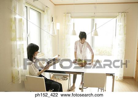 Mid adult woman reading a magazine with her daughter cleaning the table View Large Photo Image Stock Image - Mid adult woman reading a magazine with her daughter cleaning the table. Fotosearch