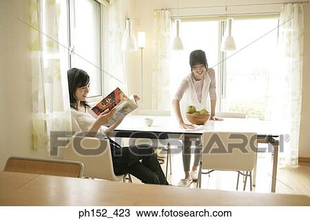 Mid adult woman reading a magazine with her daughter cleaning the table View Large Photo Image Stock Image - Mid adult woman reading a magazine with her daughter cleaning the table. Fotosearch
