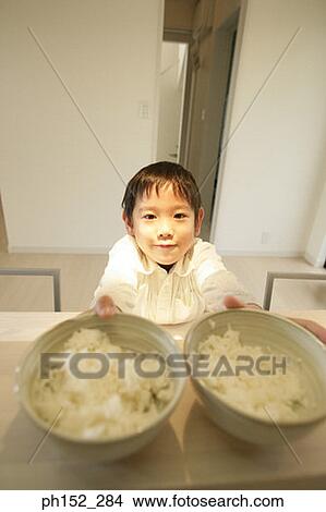 Picture - Portrait of a boy holding two bowls of food. Fotosearch