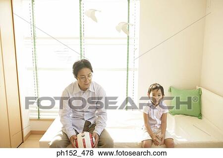 Portrait of a boy sitting on the bed with his father holding a soccer ball View Large Photo Image Stock Photo - Portrait of a boy sitting on the bed with his father holding a soccer ball. Fotosearch