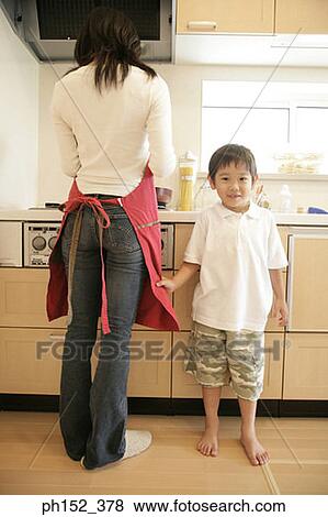 Portrait of a boy standing beside his mother in the kitchen View Large Photo Image Stock Photo - Portrait of a boy standing beside his mother in the kitchen. Fotosearch