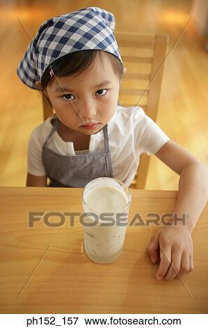 Portrait of a girl sitting at the table and drinking milk View Large Photo Image Stock Photo - Portrait of a girl sitting at the table and drinking milk. Fotosearch