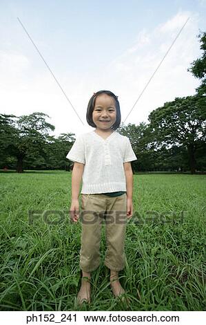 Stock Image - Portrait of a girl standing in a park. Fotosearch