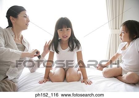 Portrait of a girl with her sister sitting on the bed and her mother brushing her hair View Large Photo Image Stock Photograph - Portrait of a girl with her sister sitting on the bed and her mother brushing her hair. Fotosearch