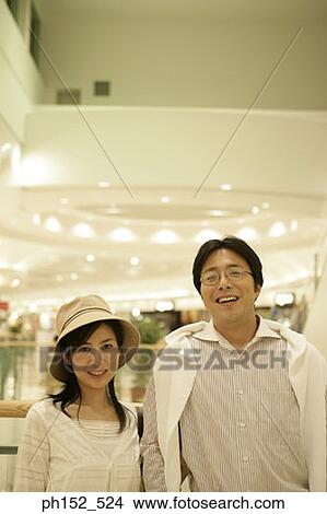 Portrait of a mid adult couple smiling in a shopping mall View Large Photo Image Picture - Portrait of a mid adult couple smiling in a shopping mall. Fotosearch