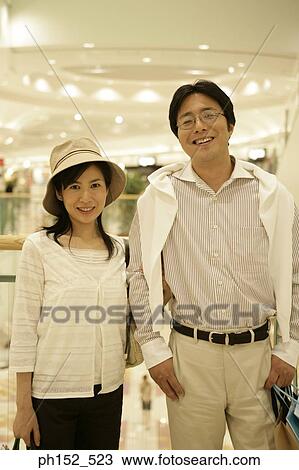 Stock Image - Portrait of a mid adult couple smiling in a shopping mall. Fotosearch