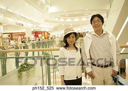 Stock Photography - Portrait of a mid adult couple smiling in a shopping mall. Fotosearch
