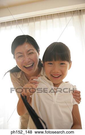 Stock Photo - Portrait of a mid adult woman and her daughter smiling. Fotosearch