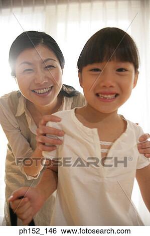 Stock Photograph - Portrait of a mid adult woman and her daughter smiling. Fotosearch