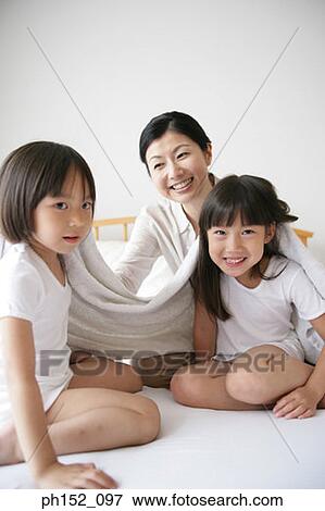 Portrait of two girls and their mother drying their hair on the bed View Large Photo Image Stock Photo - Portrait of two girls and their mother drying their hair on the bed. Fotosearch
