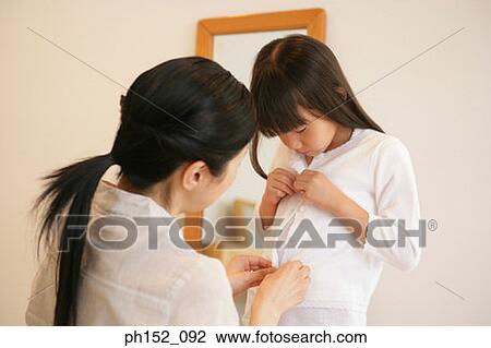 Rear view of a mid adult woman buttoning her daughter's cardigan View Large Photo Image Stock Image - Rear view of a mid adult woman buttoning her daughter's cardigan. Fotosearch