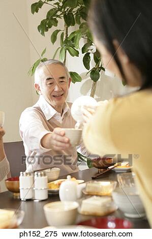 Rear view of a woman pouring tea into a senior man's cup View Large Photo Image Stock Photography - Rear view of a woman pouring tea into a senior man's cup. Fotosearch