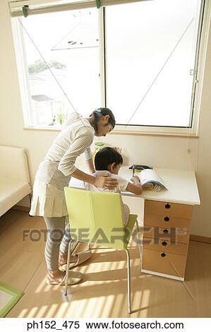 Stock Photography - Rear view of a young woman teaching her brother. Fotosearch