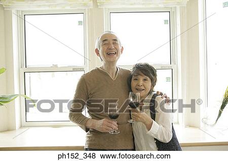 Senior couple holding glasses of red wine and smiling View Large Photo Image Stock Photo - Senior couple holding glasses of red wine and smiling. Fotosearch
