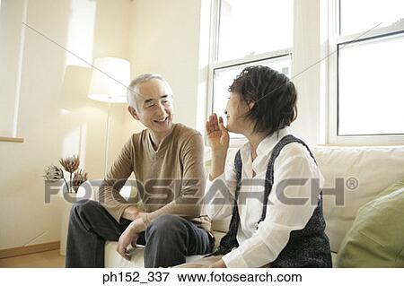 Stock Photo - Senior couple sitting on a couch and smiling. Fotosearch