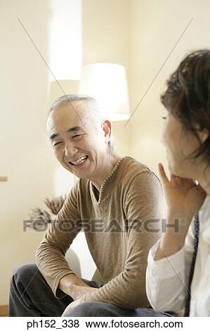 Stock Photo - Senior couple sitting on a couch and smiling. Fotosearch
