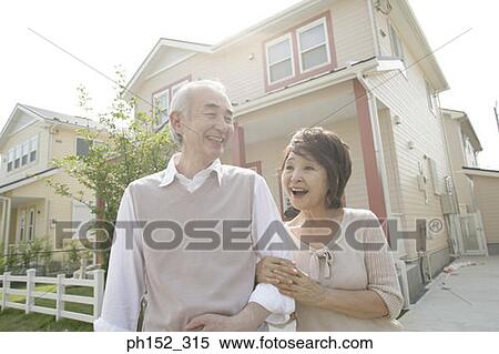 Senior couple standing arm in arm in front of a house and smiling View Large Photo Image Stock Photography - Senior couple standing arm in arm in front of a house and smiling. Fotosearch