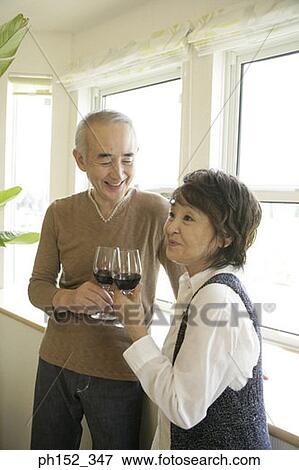 Senior couple standing near a window and holding glasses of red wine View Large Photo Image Stock Photo - Senior couple standing near a window and holding glasses of red wine. Fotosearch