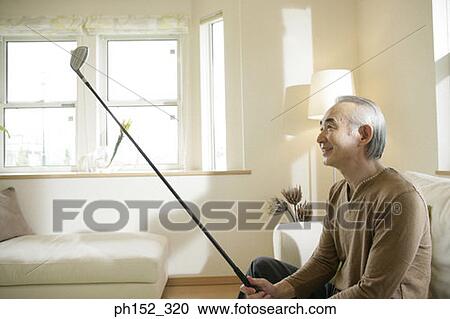 Senior man sitting on a couch and holding a golf club View Large Photo Image Stock Image - Senior man sitting on a couch and holding a golf club. Fotosearch