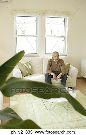 Stock Image - Senior man sitting on a couch. Fotosearch