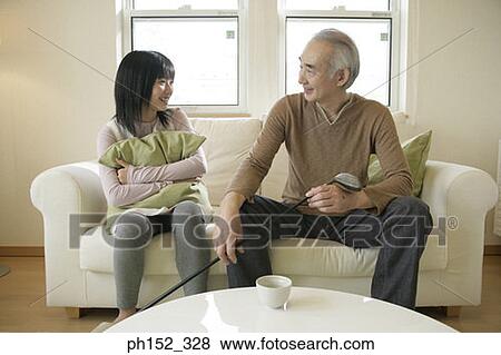 Senior man sitting on a couch with his granddaughter View Large Photo Image Stock Photo - Senior man sitting on a couch with his granddaughter. Fotosearch