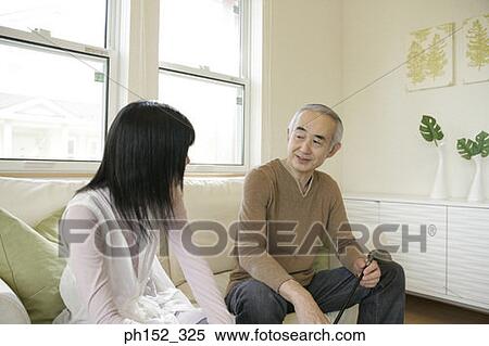 Senior man sitting on a couch with his granddaughter View Large Photo Image Stock Photography - Senior man sitting on a couch with his granddaughter. Fotosearch