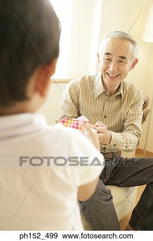Stock Photo - Senior man taking a gift from his grandson. Fotosearch