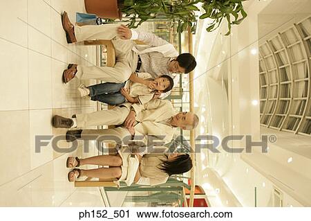 Stock Image - Senior man with his son and grandchildren sitting on a bench in a shopping mall. Fotosearch