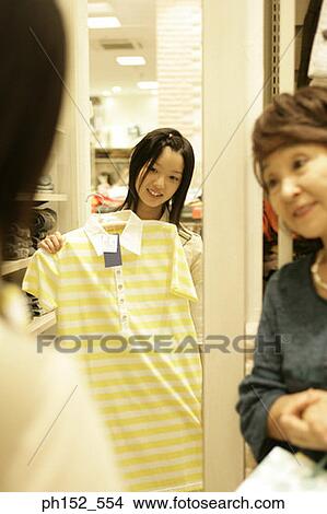 Senior woman looking at her granddaughter holding a t-shirt in a clothing store View Large Photo Image Picture - Senior woman looking at her granddaughter holding a t-shirt in a clothing store. Fotosearch