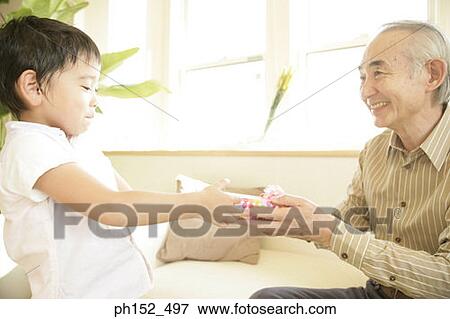Side profile of a boy giving a gift to his grandfather View Large Photo Image Stock Photo - Side profile of a boy giving a gift to his grandfather. Fotosearch