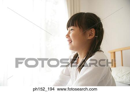 Picture - Side profile of a girl lying on the bed and smiling. Fotosearch