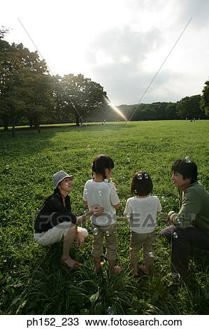 Side profile of a mid adult couple and their two daughters blowing bubbles in a park View Large Photo Image Stock Image - Side profile of a mid adult couple and their two daughters blowing bubbles in a park. Fotosearch