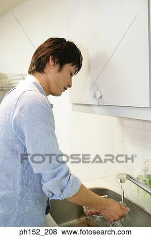 Side profile of a mid adult man washing a glass in the kitchen View Large Photo Image Stock Photo - Side profile of a mid adult man washing a glass in the kitchen. Fotosearch