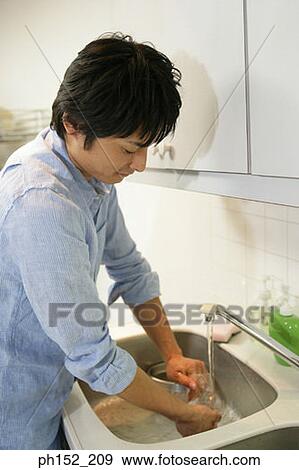 Side profile of a mid adult man washing a glass in the kitchen View Large Photo Image Stock Photo - Side profile of a mid adult man washing a glass in the kitchen. Fotosearch
