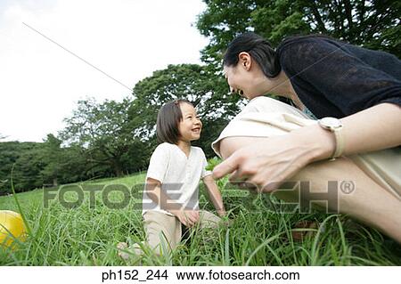Picture - Side profile of a mid adult woman and her daughter smiling. Fotosearch