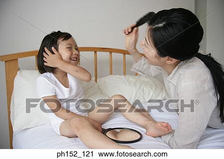 Side profile of a mid adult woman and her daughter smiling on the bed View Large Photo Image Stock Image - Side profile of a mid adult woman and her daughter smiling on the bed. Fotosearch