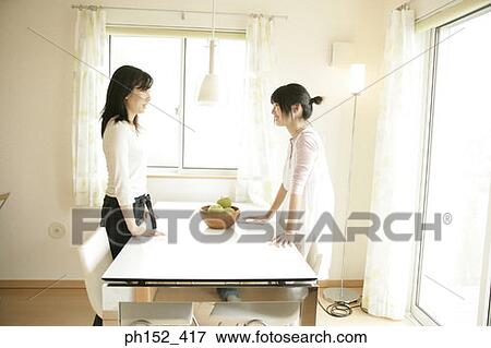 Side profile of a mid adult woman and her daughter standing beside a table and talking to each other View Large Photo Image Stock Photo - Side profile of a mid adult woman and her daughter standing beside a table and talking to each other. Fotosearch