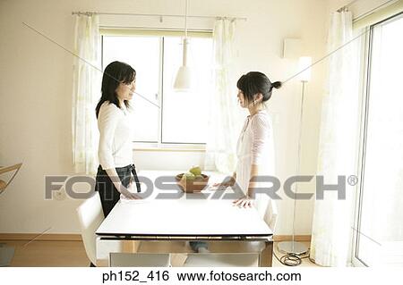 Side profile of a mid adult woman and her daughter standing beside a table and talking to each other View Large Photo Image Stock Photograph - Side profile of a mid adult woman and her daughter standing beside a table and talking to each other. Fotosearch