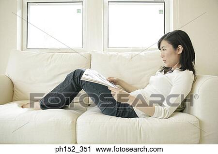 Side profile of a mid adult woman reclining on a couch and holding a magazine View Large Photo Image Stock Image - Side profile of a mid adult woman reclining on a couch and holding a magazine. Fotosearch