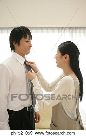 Stock Photo - Side profile of a mid adult woman adjusting a mid adult man's tie. Fotosearch